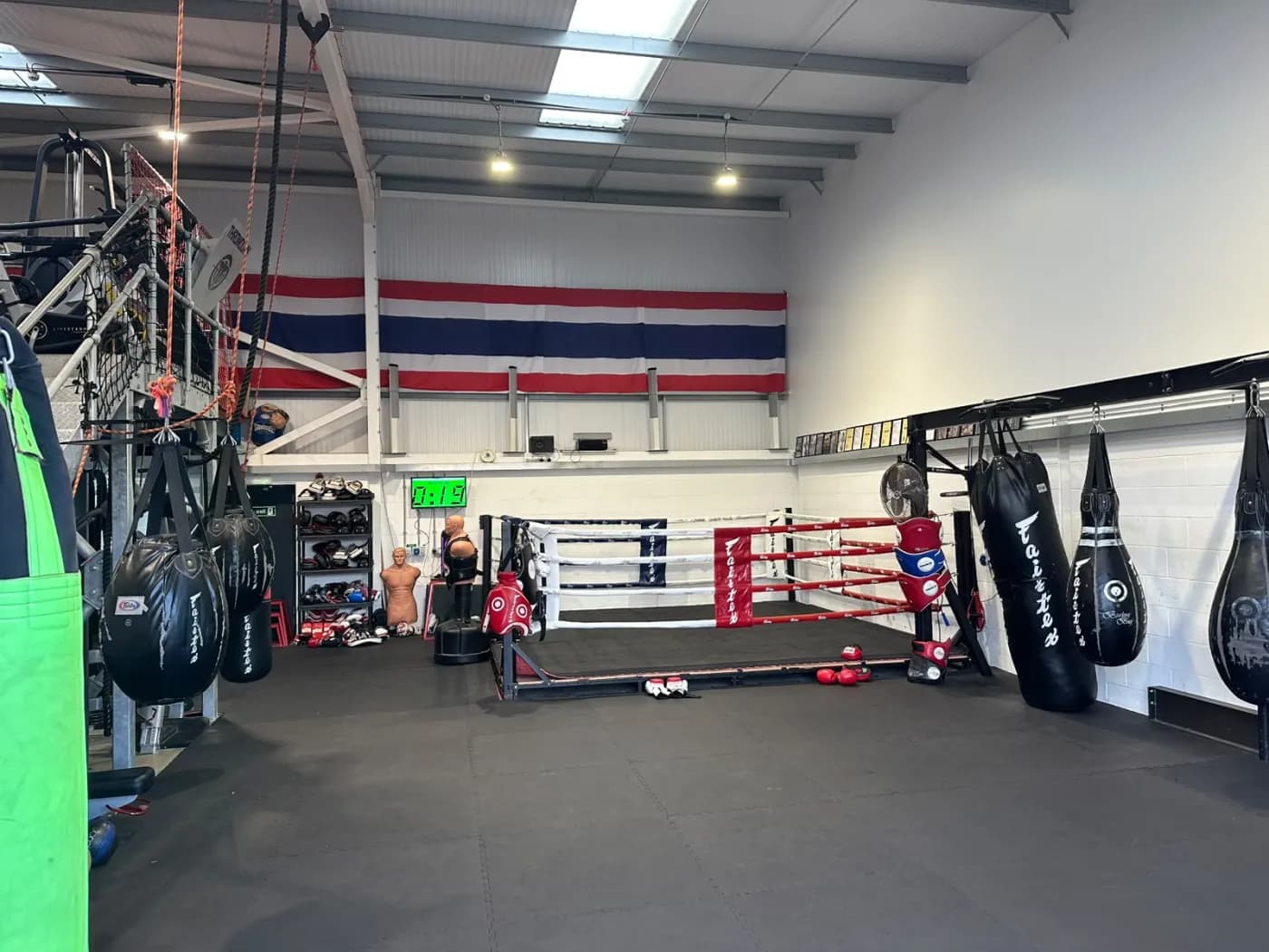 Competition ring flanked by a wall of Fairtex heavy bags